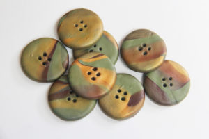 An array of polymer clay buttons in earthy tones
