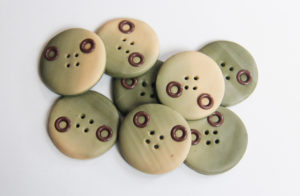 An array of polymer clay buttons in earthy tones